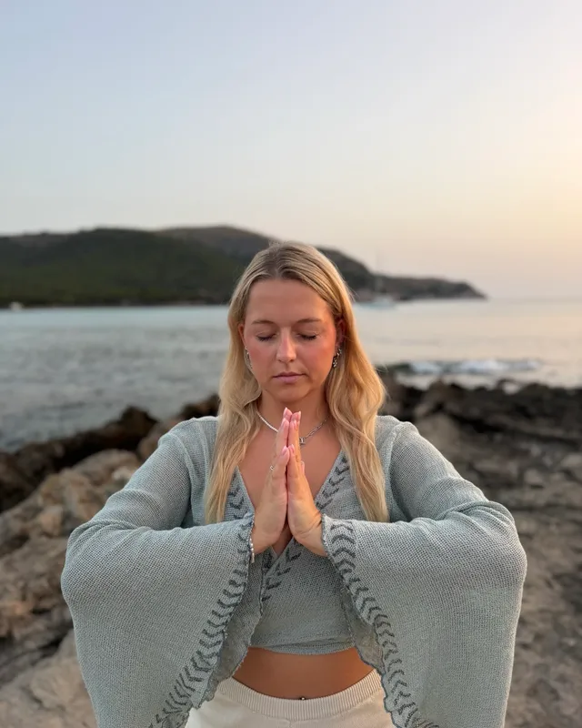 Nina Leismann meditiert mit gefalteten Händen am Meer